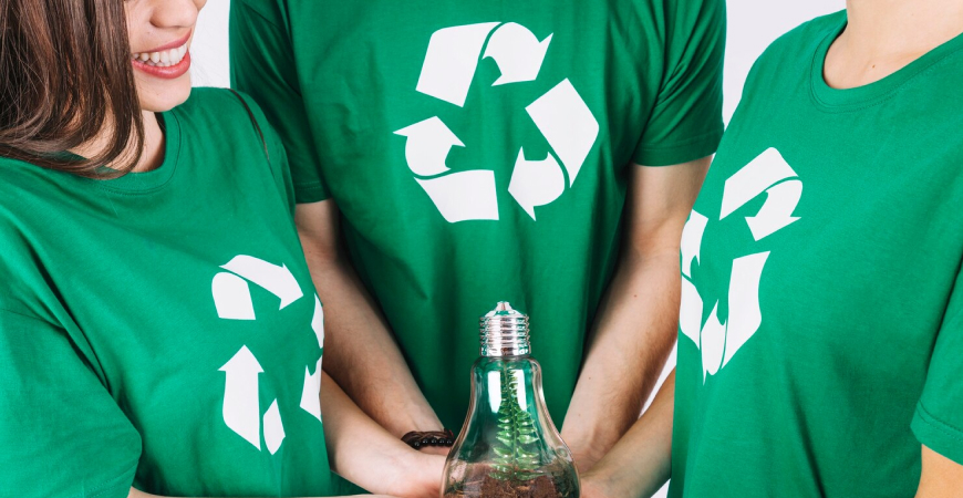 Contabilidade para área reciclagem: cooperados com camisetas verdes e símbolo de reciclagem segurando lâmpada, representando sustentabilidade.